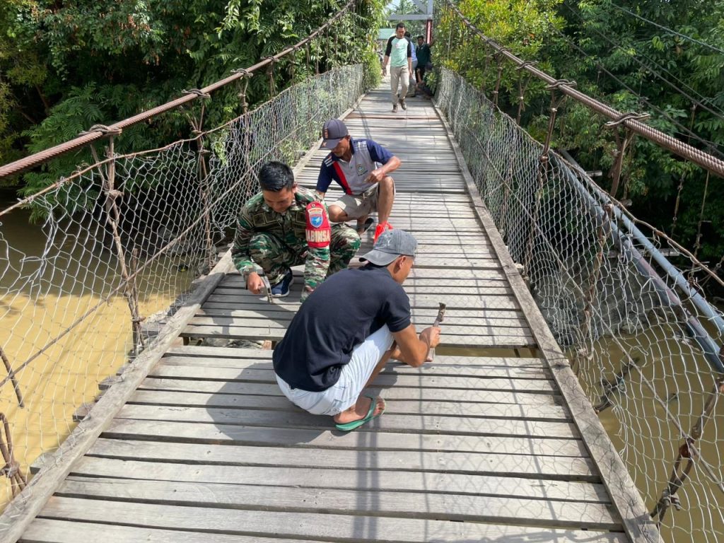 Babinsa Koramil Nanga Mahap Bersama Warga Gotong Royong Perbaiki Jembatan Penghubung Dusun