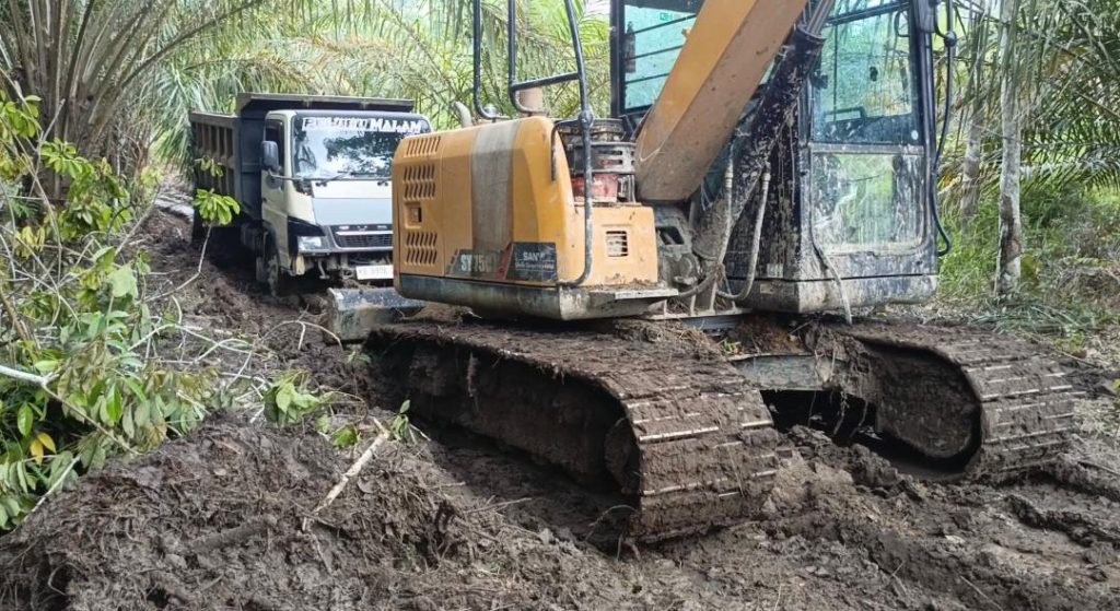 Raungan Mesin Excavator Menarik Truk Pembawa Material untuk Pembuatan Rabat Beton